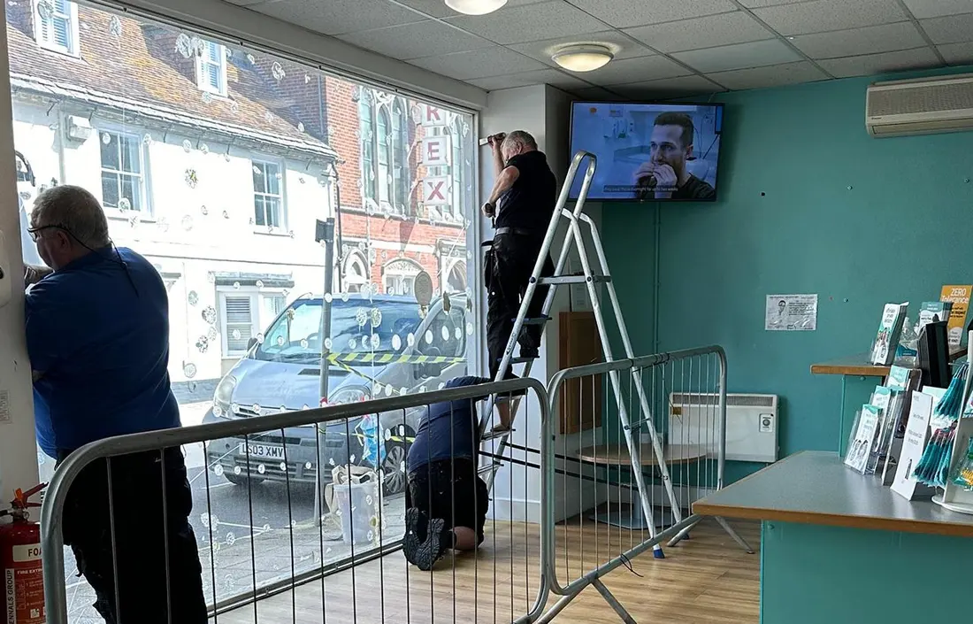 Operatives replacing a broken window in a dental surgery reception