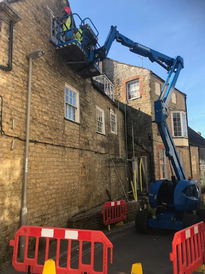 Access platform reaching a high brick wall for exterior building works